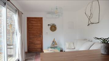 Una sala de estar moderna con una puerta de madera, un sofá blanco, una mesa de madera y un colgador de luz.