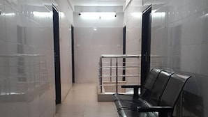 Un pasillo con un banco, paredes de baldosas y una puerta al final.