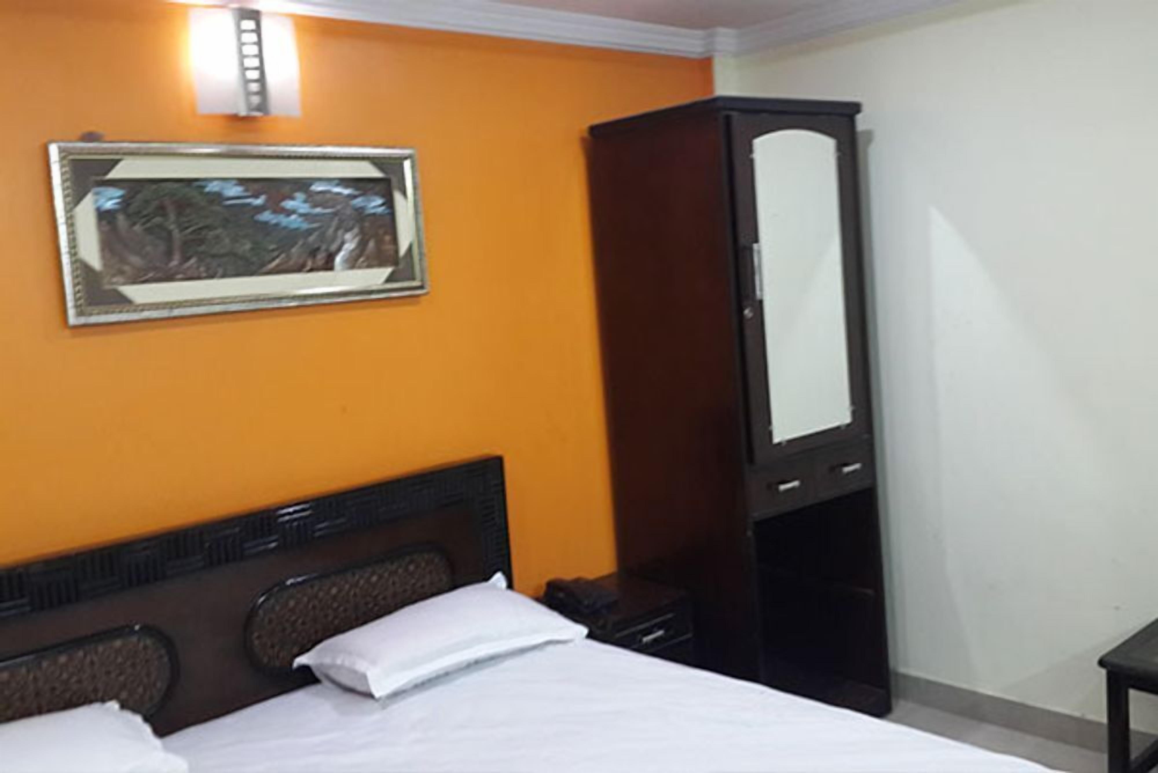 A hotel room with a bed, a nightstand, a wardrobe, and a framed picture on the wall.