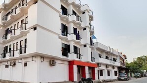 Un edificio de varios pisos con balcones, unidades de aire acondicionado y un toldo rojo.