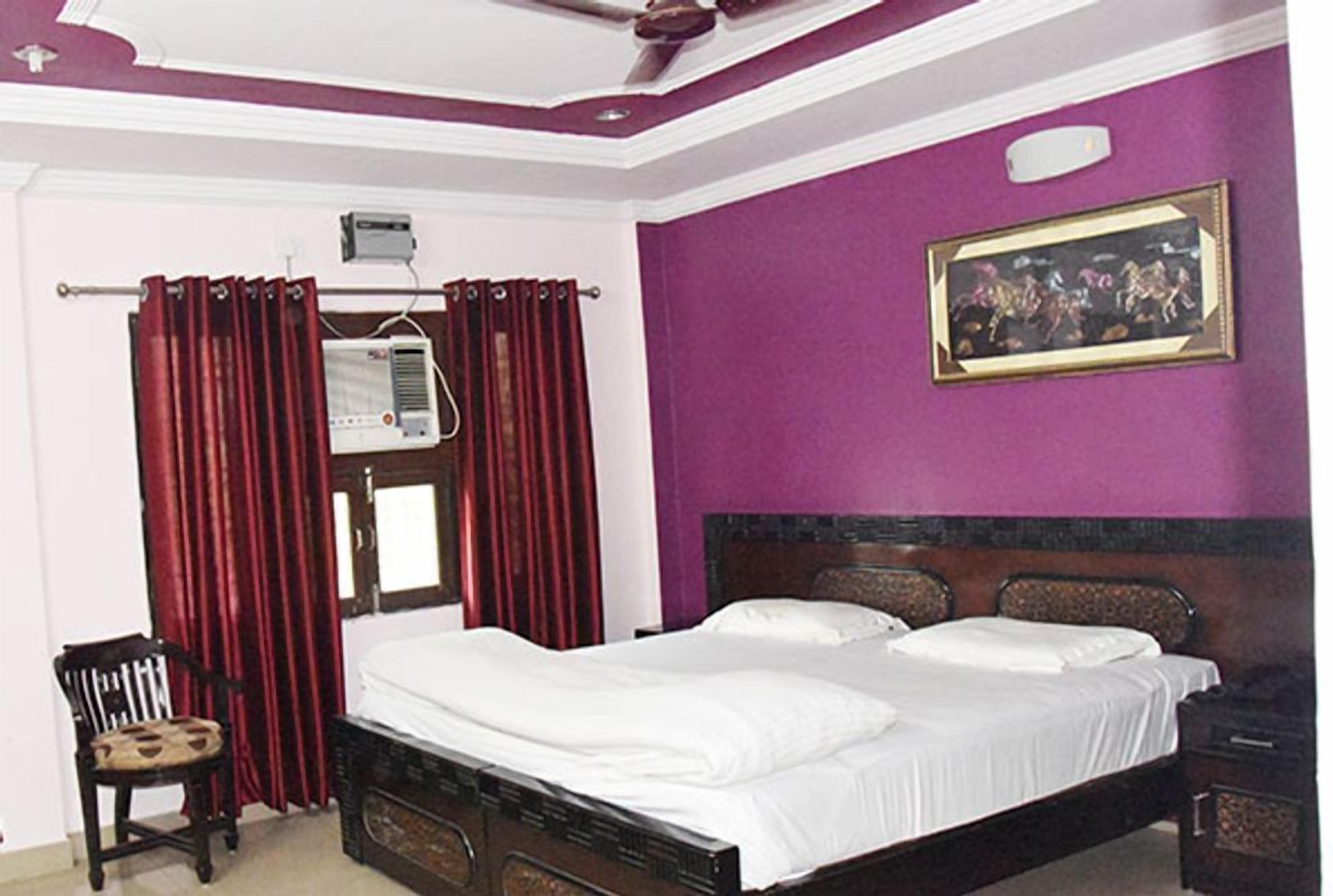 A bedroom with a bed, a chair, a heater, and a painting on the wall.