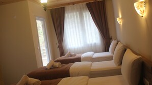 A hotel room with two beds, each with a pillow and a rolled towel. There is a window with curtains, and a door is visible on the left side. - Vulada Butik Otel (Ardesen)