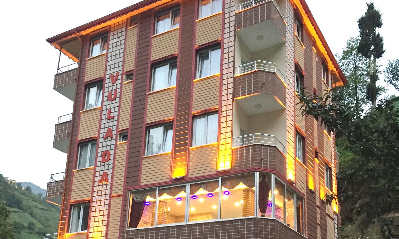 Un hôtel à plusieurs étages, dont la façade est ornée d’une grande enseigne « VULADA ».