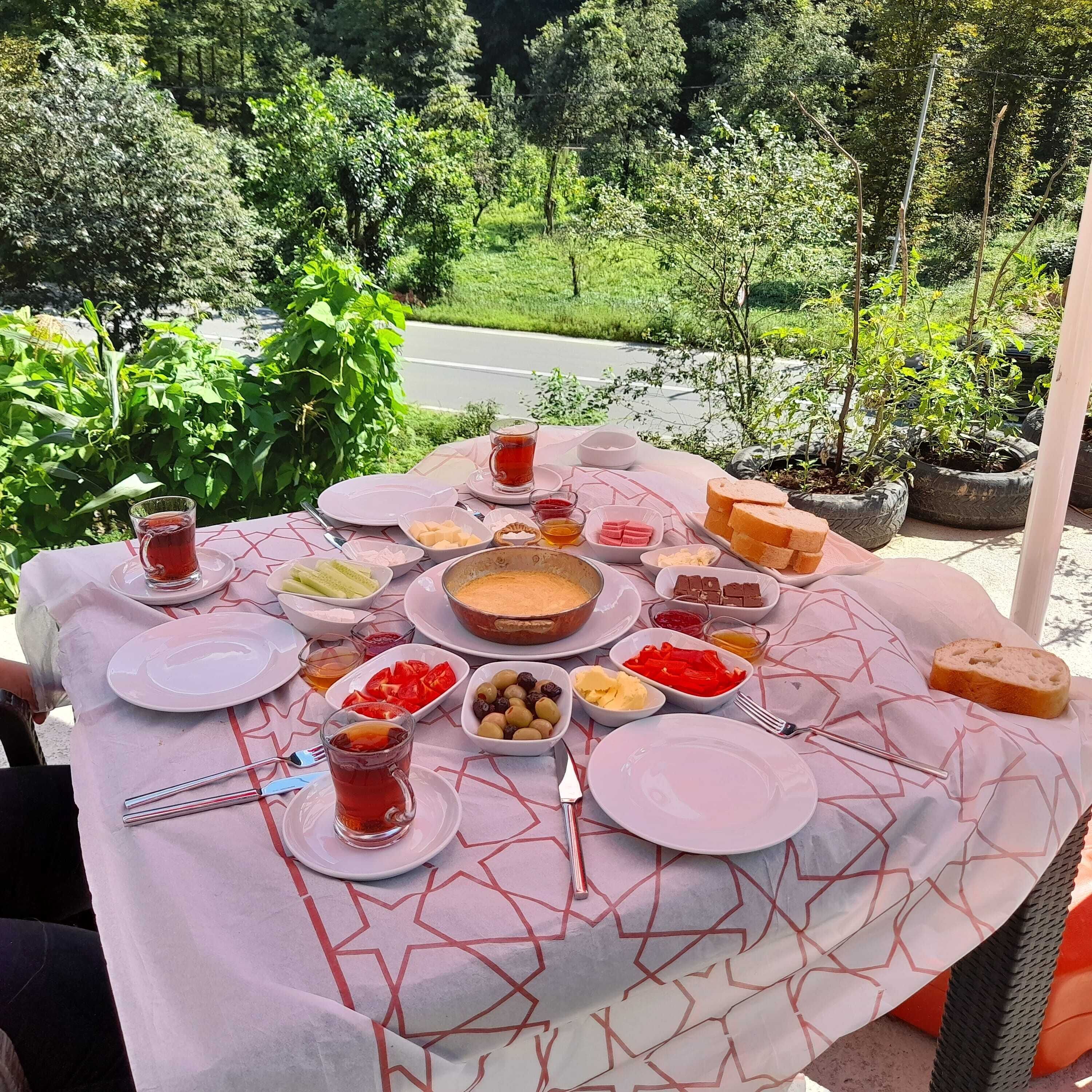 A table set outdoors with various dishes and a view of a road and greenery in the background.