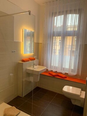 A modern bathroom with a glass shower enclosure, a white sink, and a toilet. - PensioNett (Bernburg)