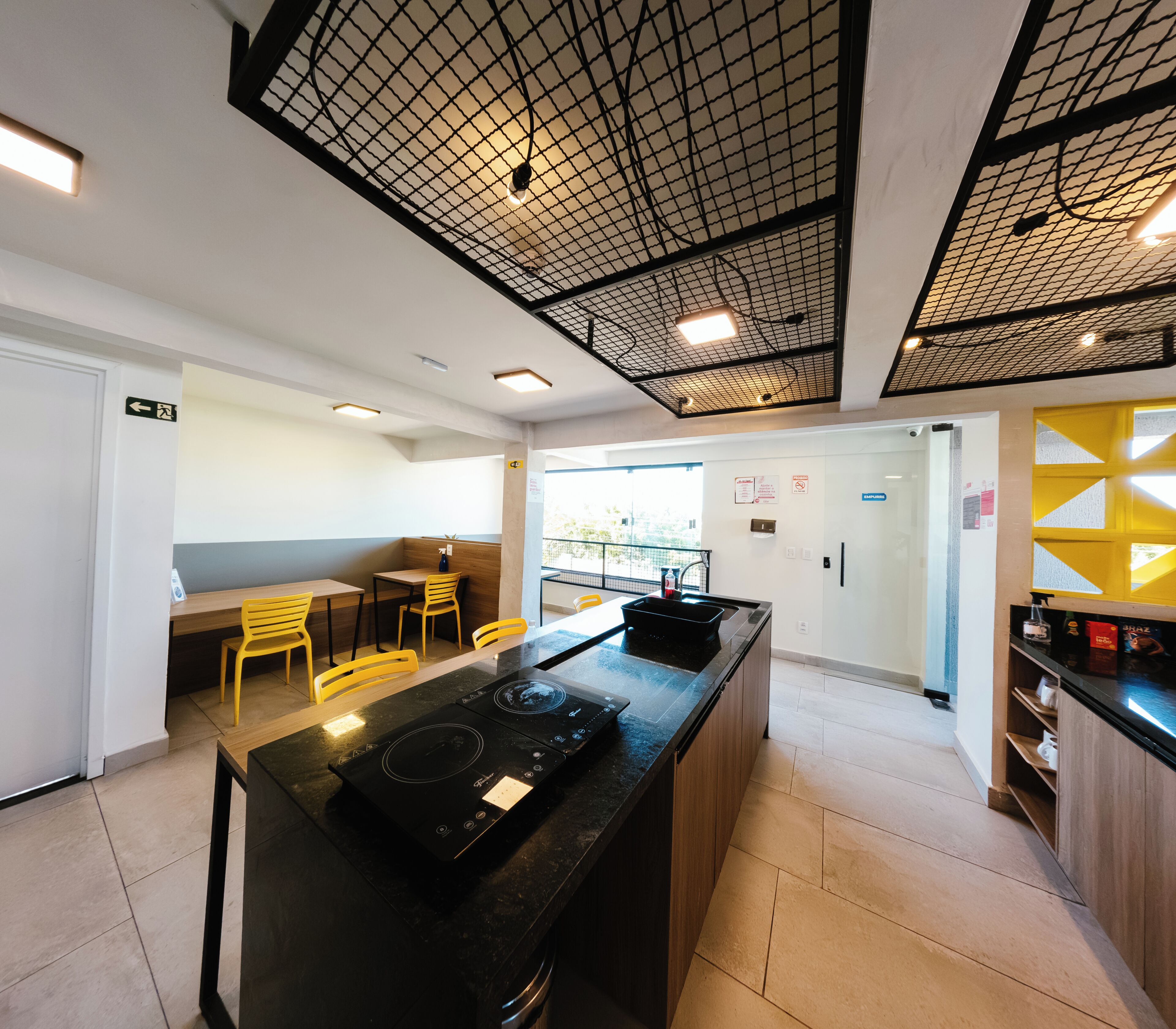 A modern kitchen with a central island, yellow chairs, and a black countertop.