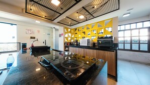 A modern kitchen with a central island, a yellow accent wall, and a large window providing natural light. - Liiv Cobogó - Natal Ponta Negra (Natal)