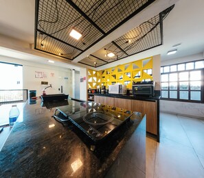 Una cocina moderna con una isla central, una pared de acento amarilla y un amplio ventanal que proporciona luz natural.