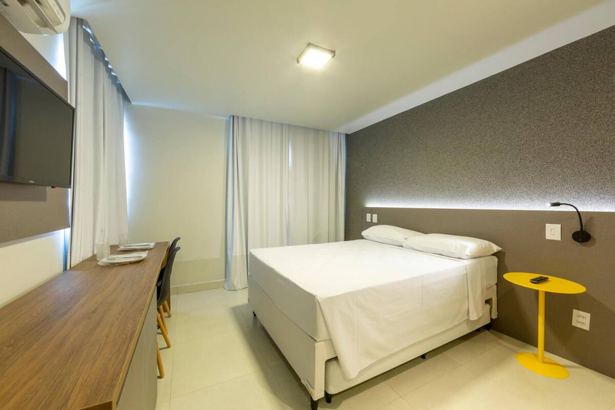 Una habitación de hotel moderna con cama, escritorio y una pequeña mesa.