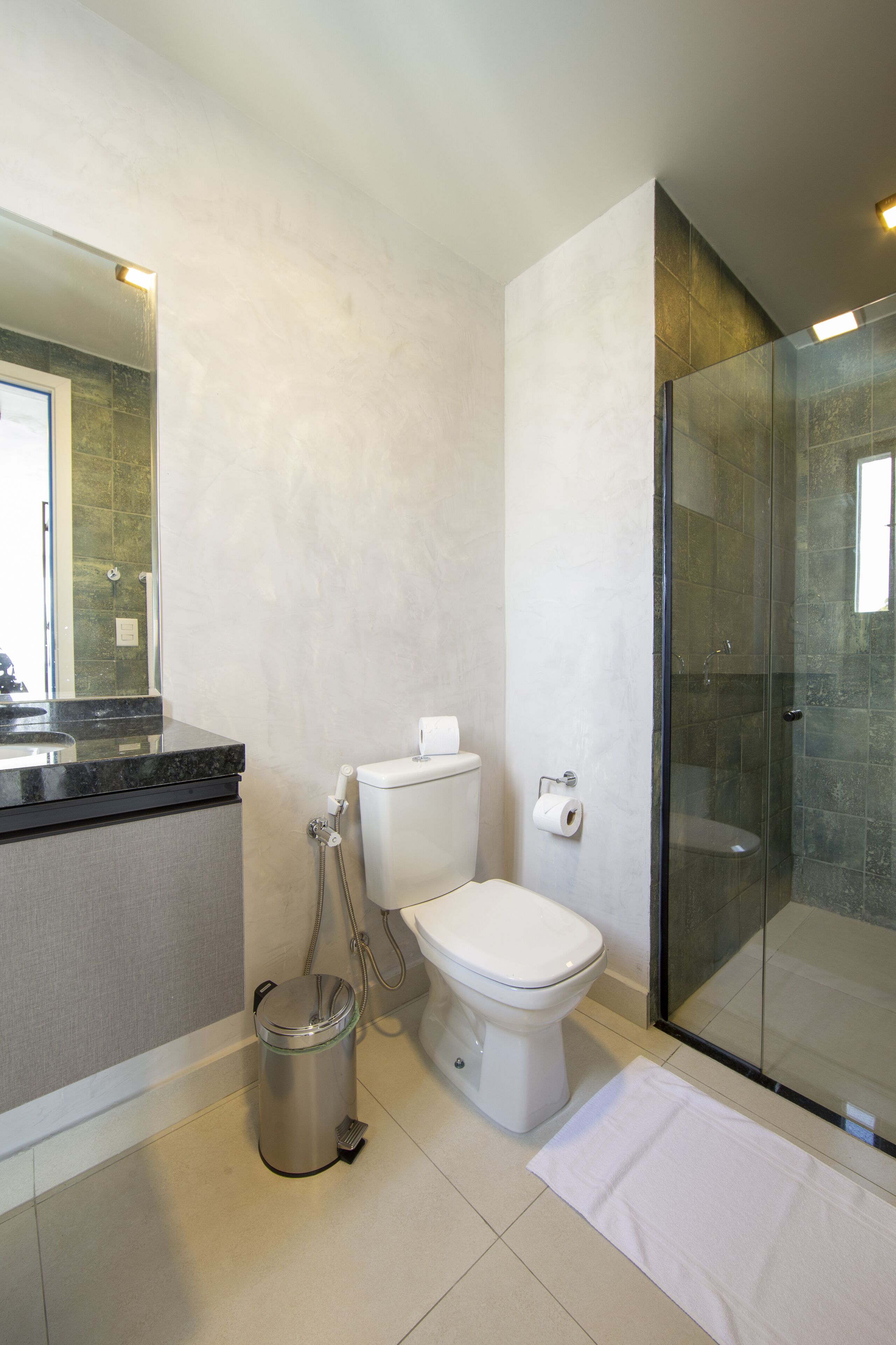 Un baño moderno con cabina de ducha de vidrio, inodoro y cubo de basura.