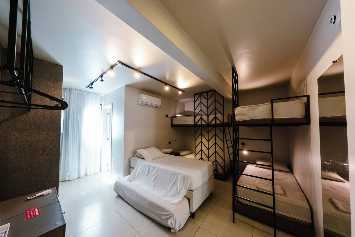 Habitación de hotel pequeña con literas, un escritorio y una cama.