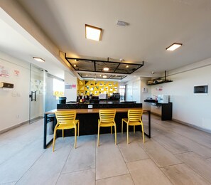 A modern kitchen with a central island, yellow chairs, and a glass partition.