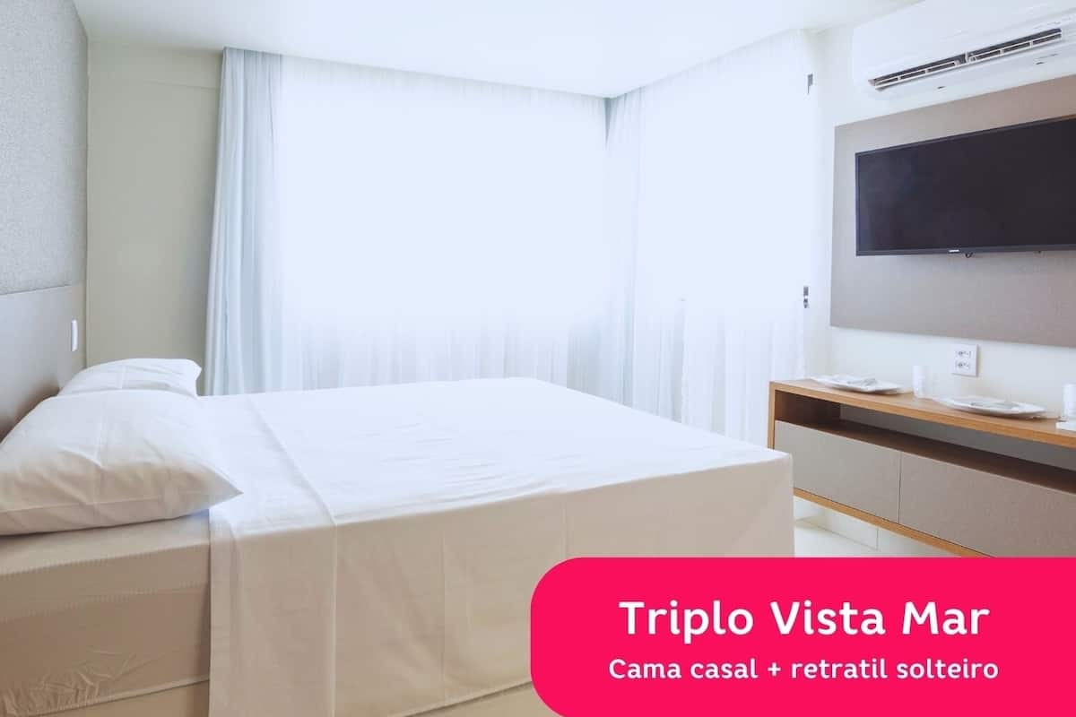 Habitación de hotel con cama, televisión y ventana con cortinas.