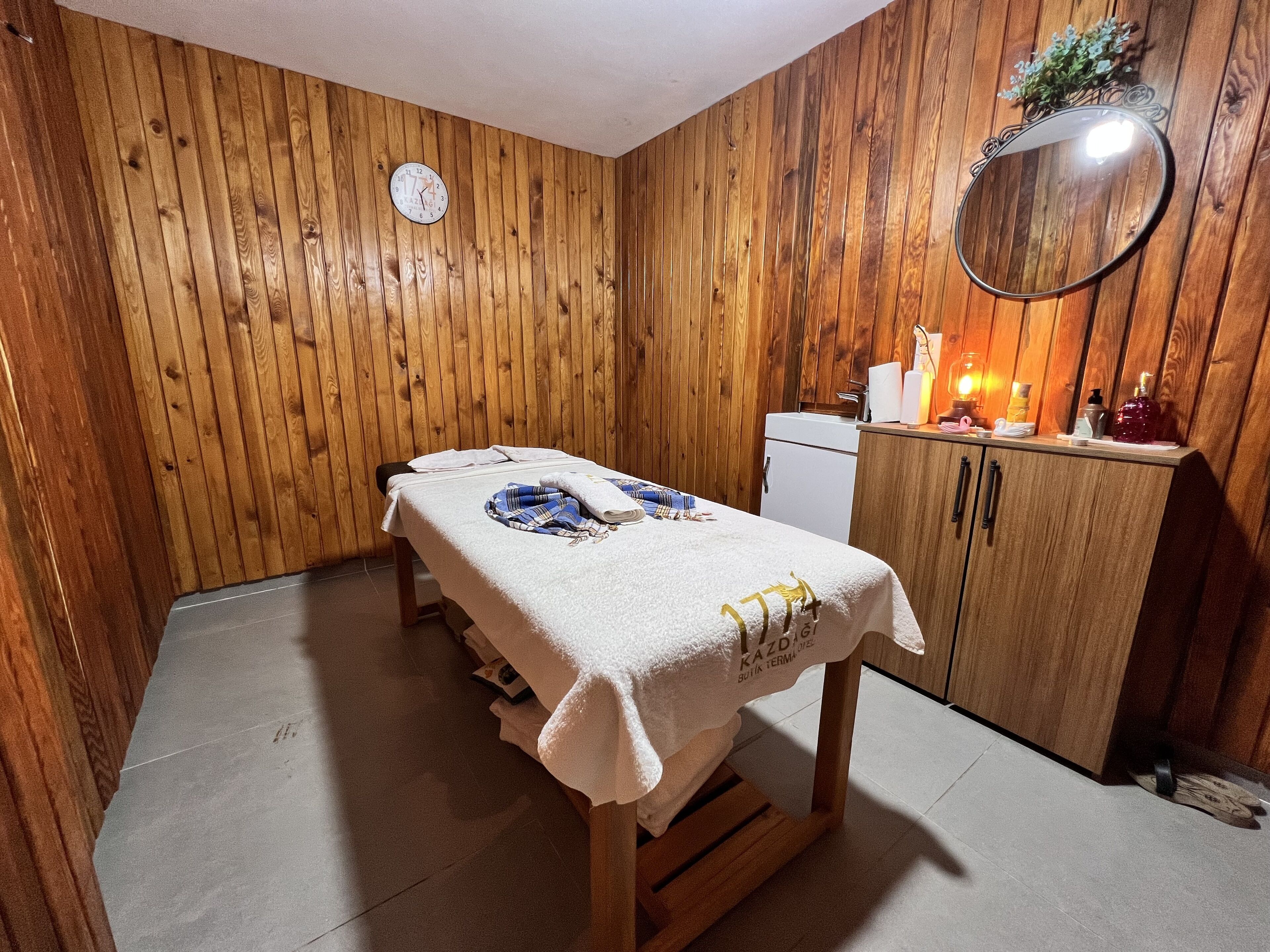 A wooden-paneled room with a bed, a small desk, and a mirror.