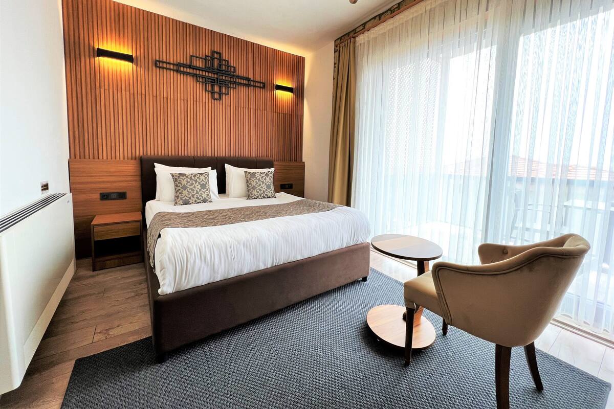 Ein modernes Hotelzimmer mit einem großen Bett, einem kleinen runden Tisch und einem Sessel.