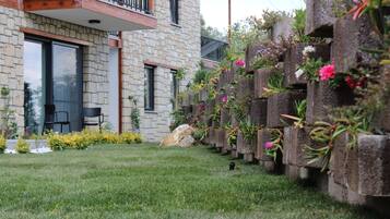 A stone building with a balcony, a grassy lawn, and a flower wall.