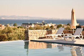 A swimming pool with lounge chairs and an umbrella, overlooking a cityscape and the sea. - 1774 Kazdagi Termal Otel (Edremit)