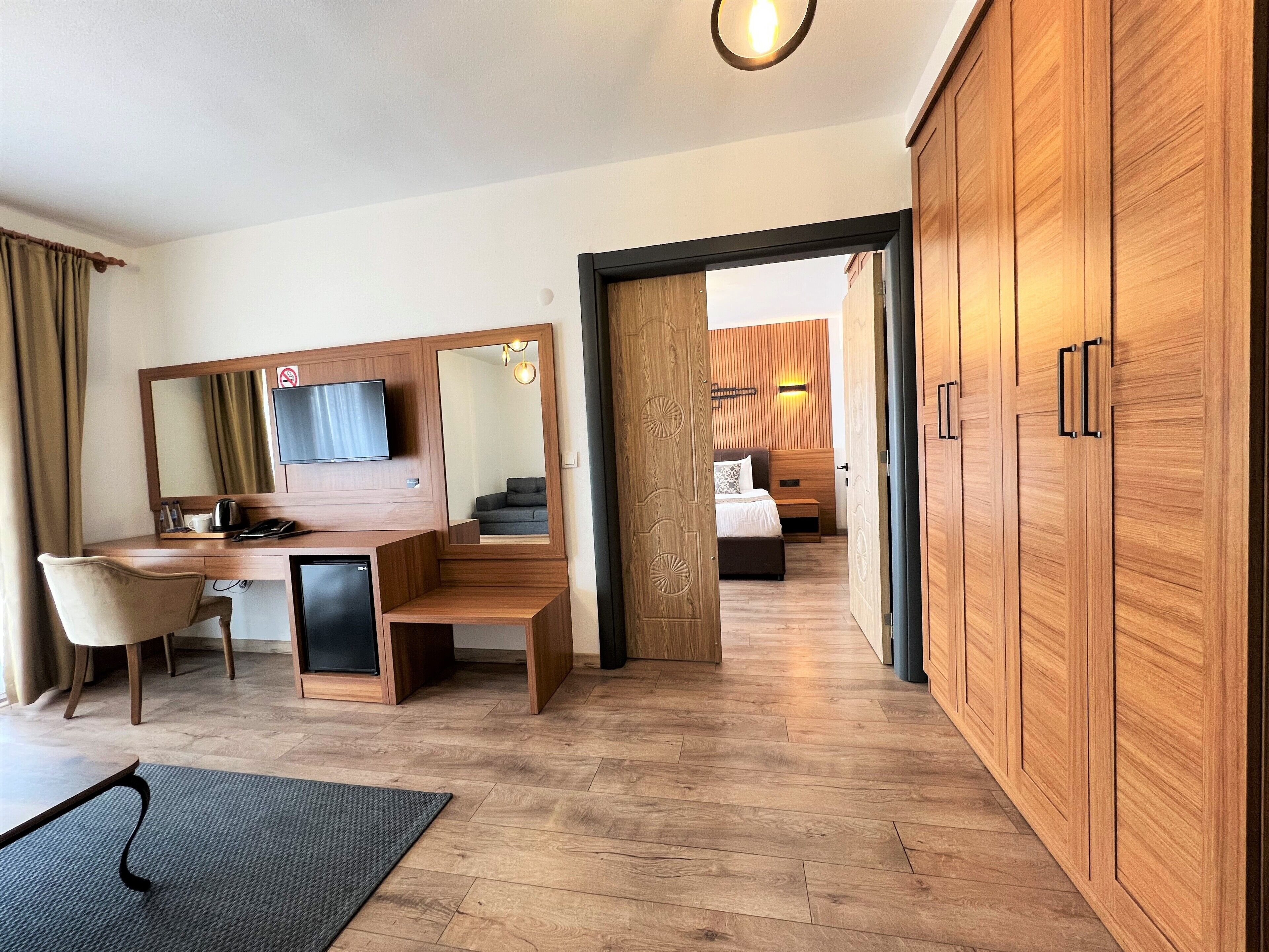 Una habitación de hotel con un escritorio de madera, una silla, una cama y un armario.