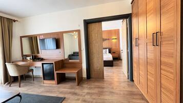 Una habitación de hotel con un escritorio de madera, una silla, una cama y un armario.