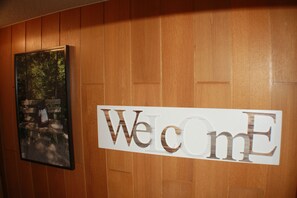A wooden wall with a 'Welcome' sign and a framed picture of a bench in a forest. - Haus Wegener (Bad Sassendorf)