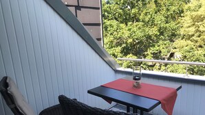 A balcony with a wicker chair and a small table with a red tablecloth. - Fewo im Josefinum (Bad Sassendorf)