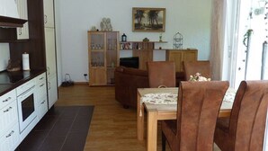 A living room with a dining area, wooden cabinets, a bookshelf, and a painting on the wall. - Fewo im Josefinum (Bad Sassendorf)
