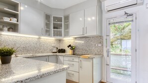 A modern kitchen with granite countertops, white cabinetry, and a built-in oven. - MALLORCA 8 Canyelles Roses (Rosas / Roses)