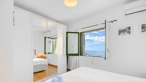 A bedroom with a bed, a mirror, a window with a view of the sea, and a wardrobe. - MALLORCA 8 Canyelles Roses (Rosas / Roses)