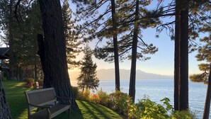 Un banc situé dans un espace verdoyant, d’où l’on peut admirer un lac et des montagnes au loin.