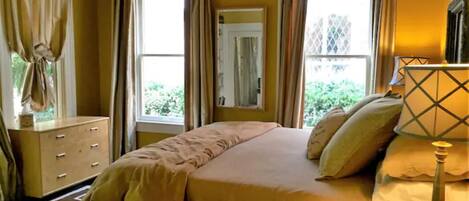 A bedroom with a bed, curtains, a dresser, and a lamp.