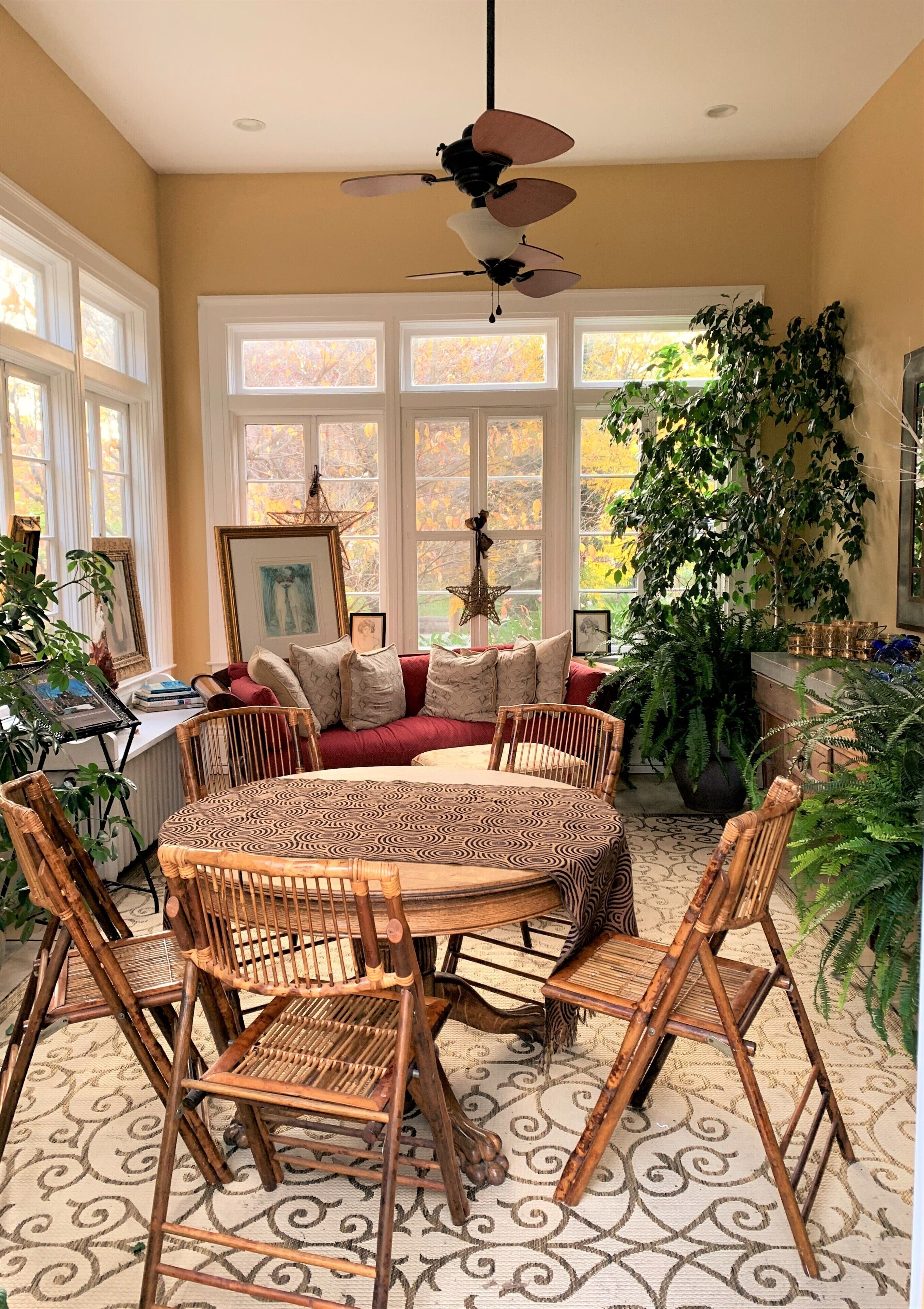 A dining area with a round table, chairs, and a ceiling fan.