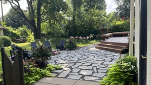 A stone patio leading to a wooden deck with Adirondack chairs and a staircase. - Historic Mansion-Modern Amenities, Sauna, Fire Pit, Hot Tub, Deck, Walk to Dine (Louisville)