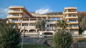 A multi-story hotel with balconies, a central courtyard, and a stone facade. - One Bedroom Apartment with Sea View (Pržno)