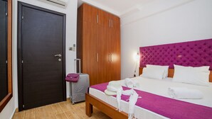 A hotel room with a bed, wooden wardrobe, and a suitcase. - One Bedroom Apartment with Sea View (Pržno)