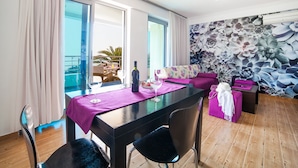A modern living room with a dining area, large windows, and a balcony with outdoor furniture. - One Bedroom Apartment with Sea View (Pržno)