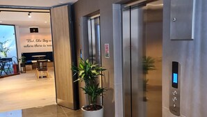 A modern elevator with a digital display, a potted plant, and a wall with a motivational quote. - Ivy Hotel - Adults Only (St. Julian's)