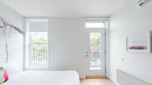 Une chambre à coucher avec un lit, une porte donnant sur un balcon et une fenêtre.