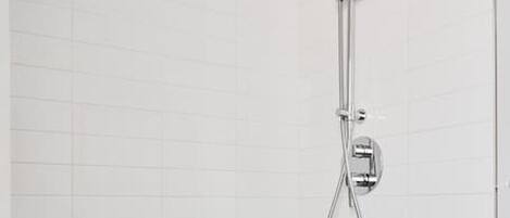 A modern bathroom with a white tiled wall, a freestanding bathtub, and a shower with a handheld showerhead and a wall-mounted faucet.