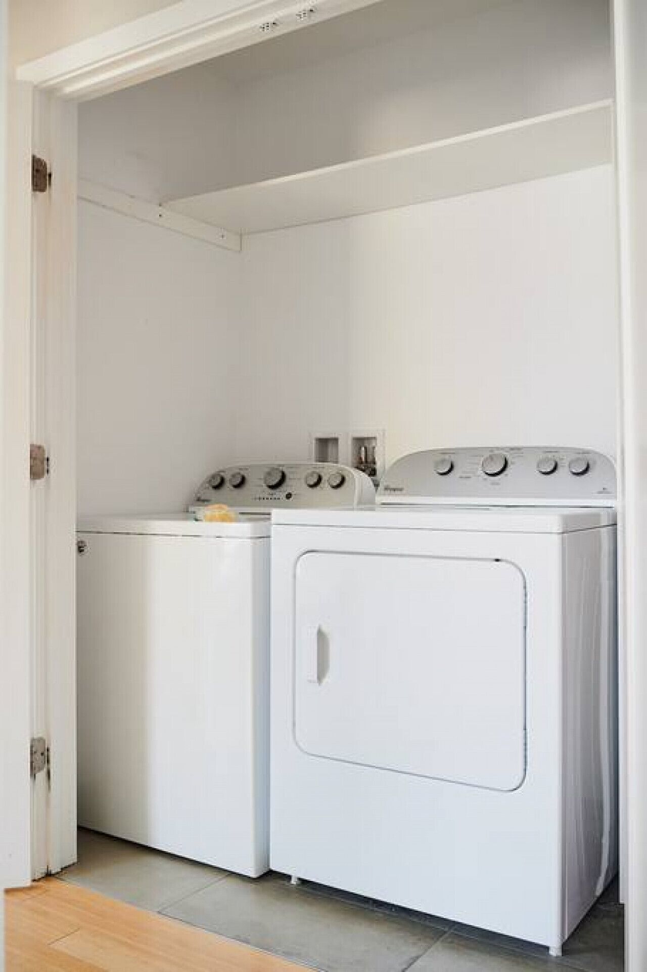 A laundry room with two white washing machines and a dryer.