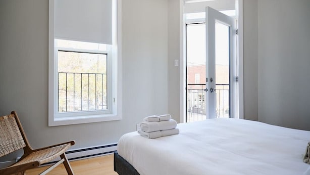 A bedroom with a bed, a chair, and a window.