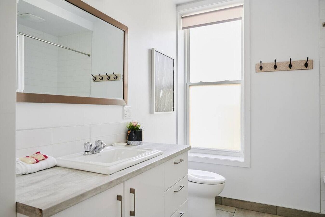Un baño moderno con un espejo grande, un lavabo, un inodoro y una ventana.