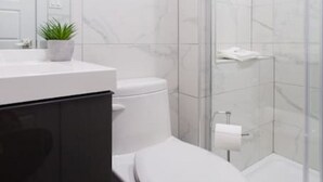 Ein modernes Badezimmer mit Toilette, Waschbecken und Duschbereich.