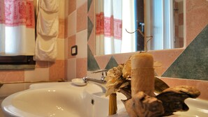 Un baño con un lavamanos blanco, un espejo y un perchero para toallas.