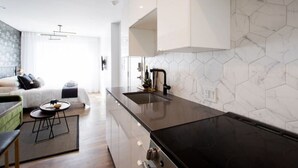 Una cocina moderna con encimera negra, salpicadero de azulejos hexagonales y estufa integrada.