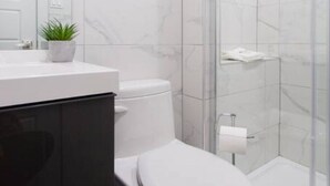 Un baño con inodoro, lavamanos y ducha.