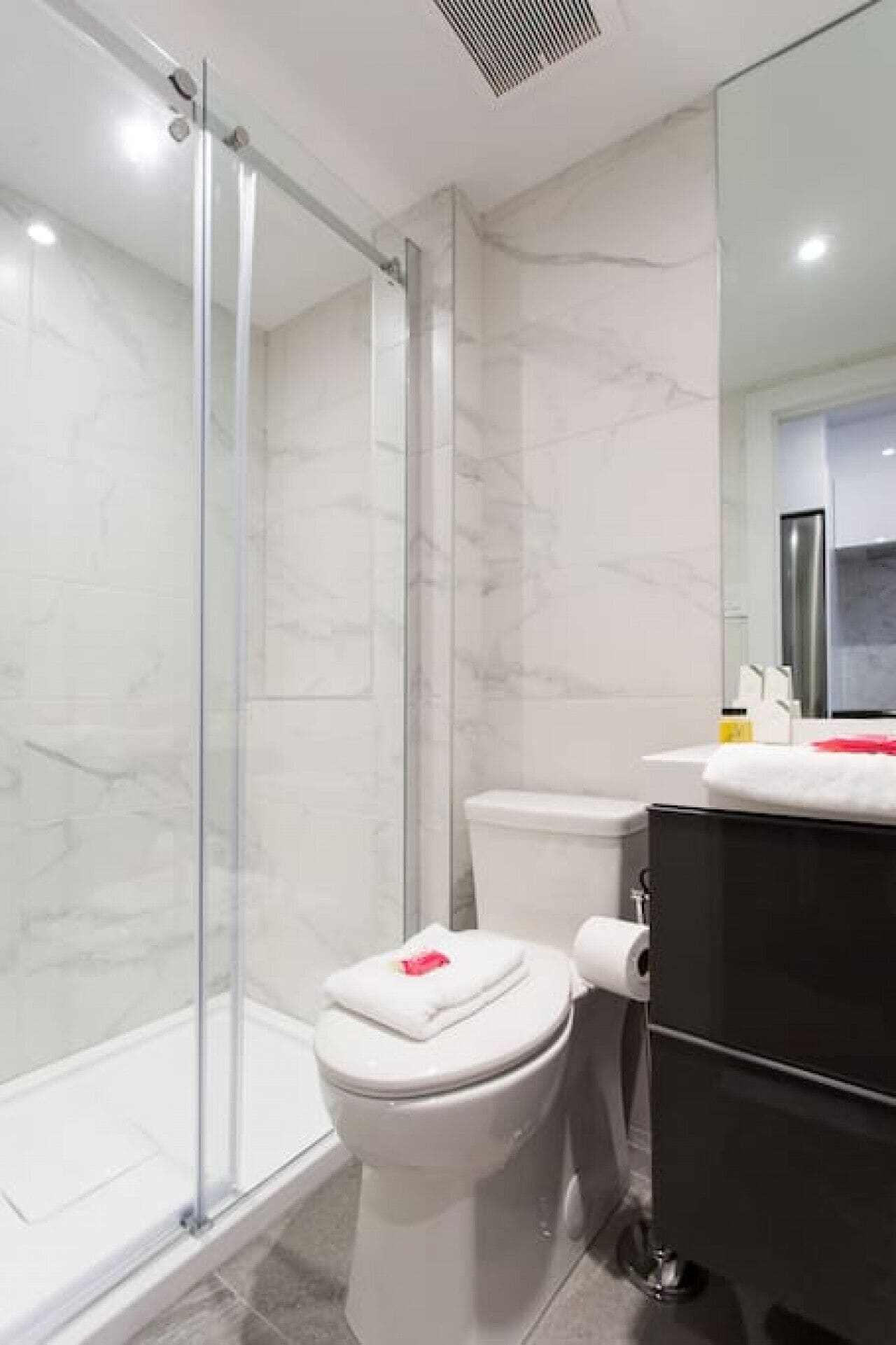 Une salle de bain moderne avec une douche à parois de verre, des toilettes et un meuble-lavabo noir.