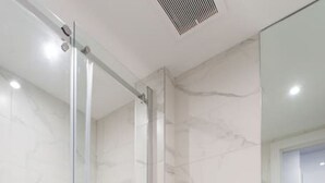 Un baño moderno con cabina de ducha de vidrio, inodoro y tocador negro.