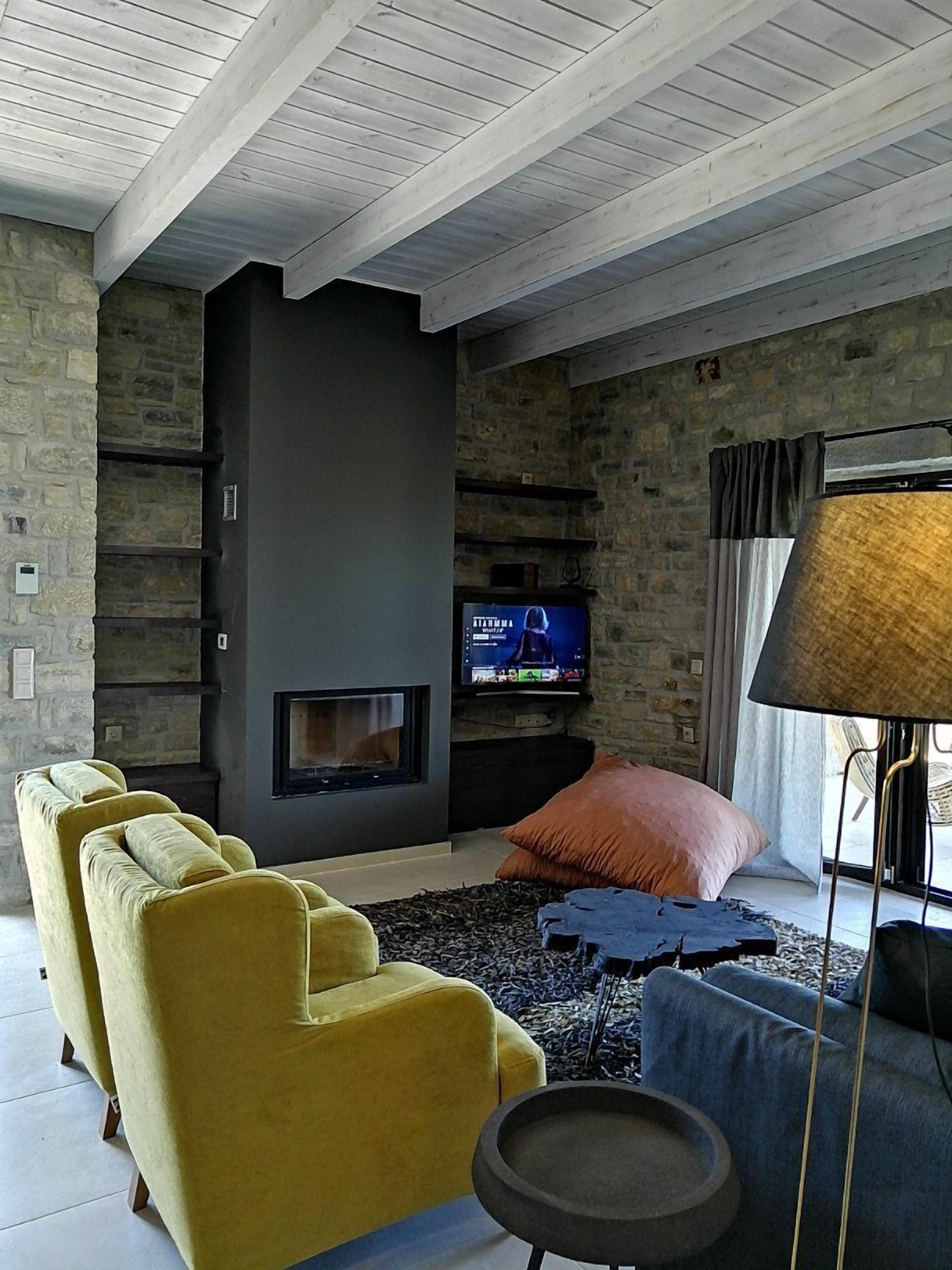 Een moderne woonkamer met een stenen muur, een open haard, een televisie en een bank.