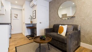 A modern living room with a grey sofa, a round coffee table, and a large mirror on the wall.