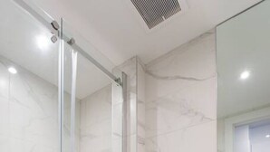 A modern bathroom with a glass shower enclosure, a white toilet, and a black vanity with a mirror.